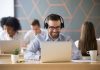 Smiling businessman wearing headphones watching video or consult